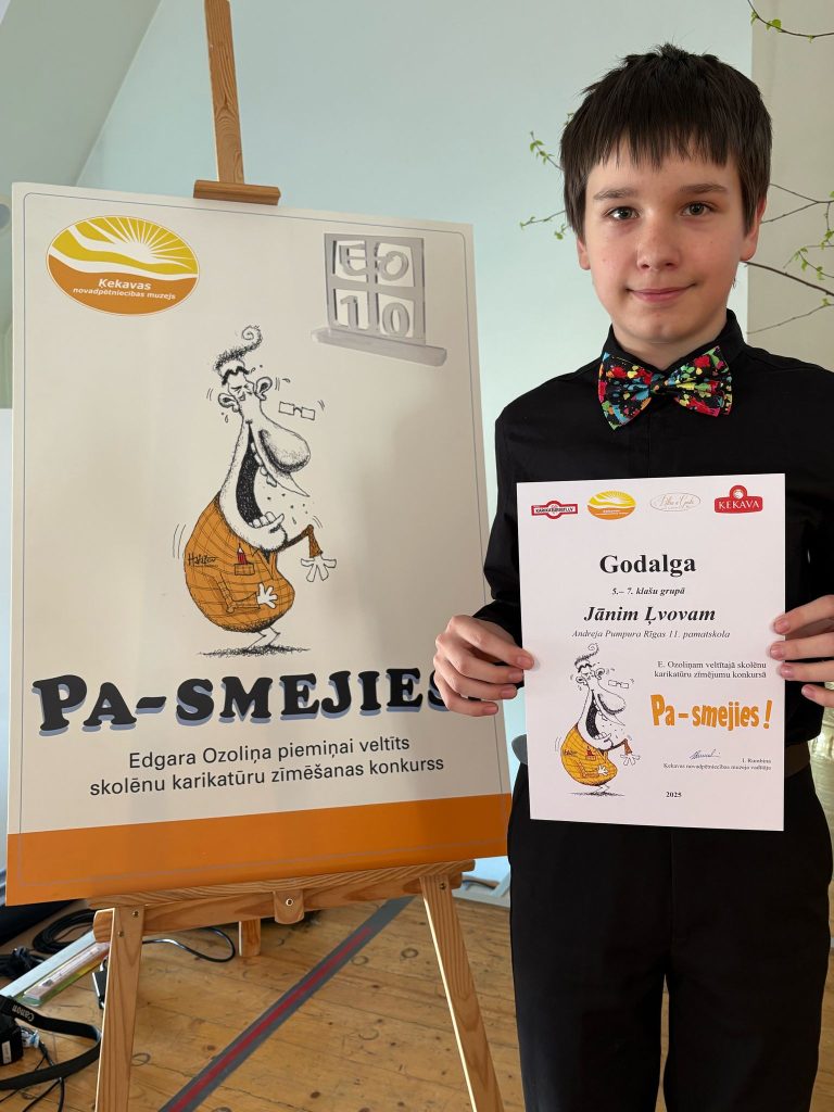 Skolēns ar diplomu pie konkursa "Pa-smejies" plakāta